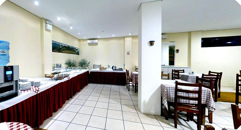 Salão do café da manhã com buffet e mesas com toalhas xadrez