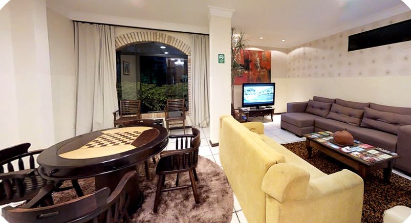 Lobby com sofás, mesa de jogos e TV