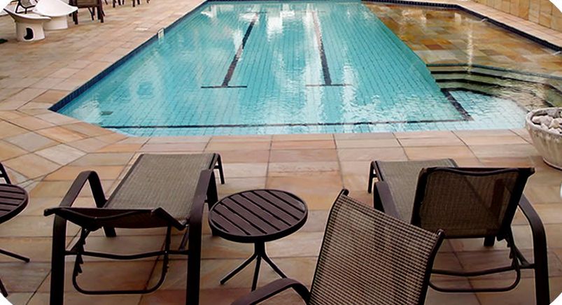 Piscina de 15 metros com deck de pedra e espreguiçadeiras
