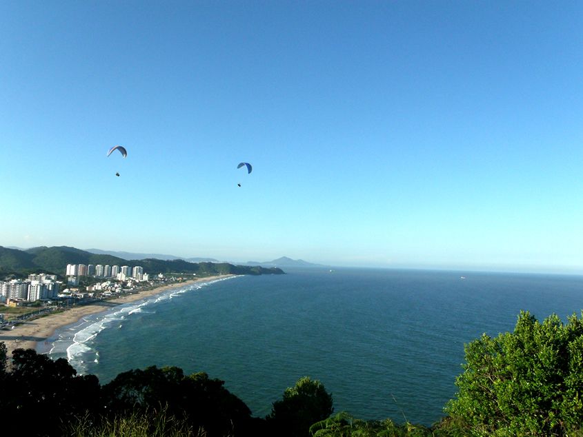 Parapentes sobrevoando a Praia Brava vista do alto do Morro do Careca