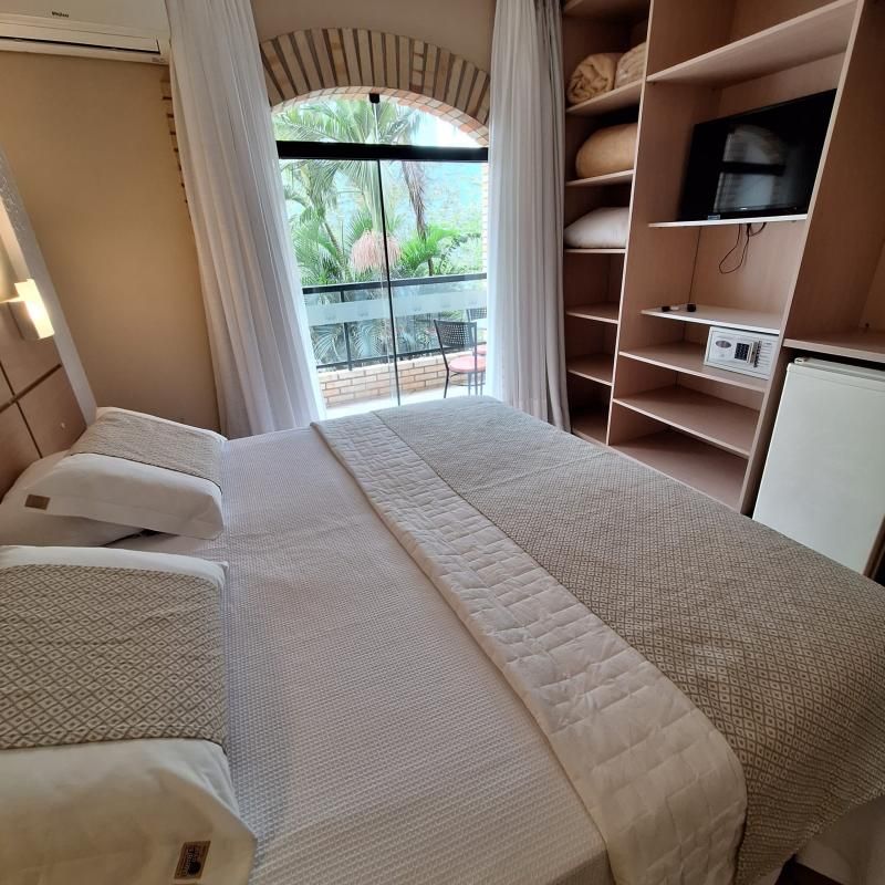 Suíte Dupla com cama de casal, enxoval branco e janela em arco